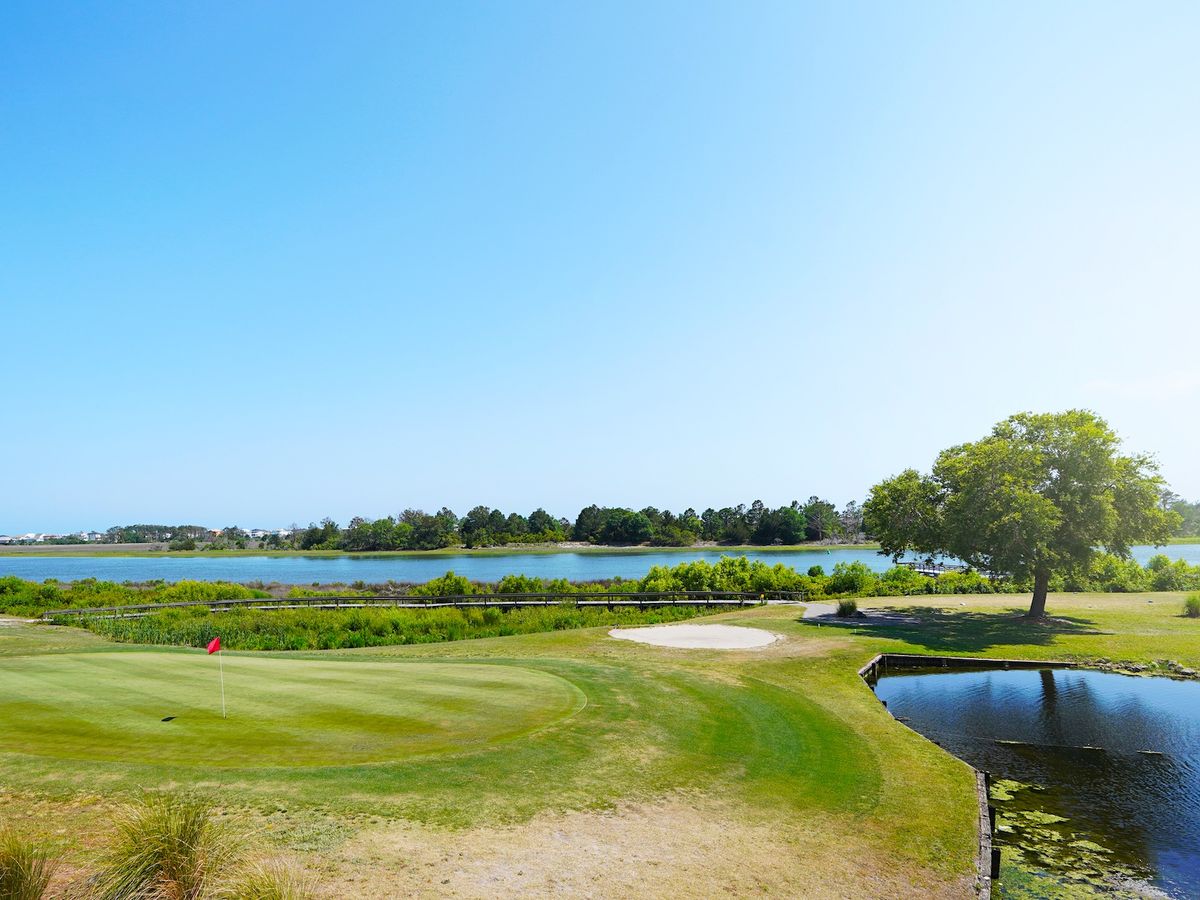 Golf course with large trees and bodies of water surrounding it