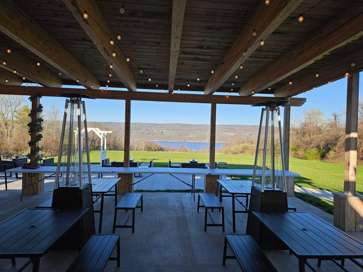A covered patio at Seneca Lake Brewing Co. offers long tables, string lights, and wide views of the lake and hills. This space is ideal for relaxed afternoons with craft beer and friends.