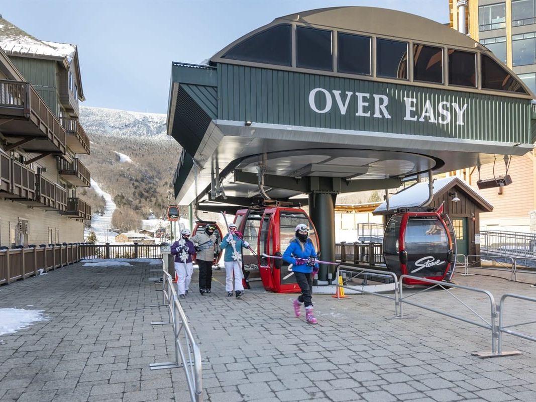 Steam rises from a heated outdoor pool as skiers unwind beneath the snow-covered trails of Mount Mansfield. The green mountain resort stands tall beside the pool, offering the perfect mix of adventure and relaxation in Stowe’s winter wonderland.