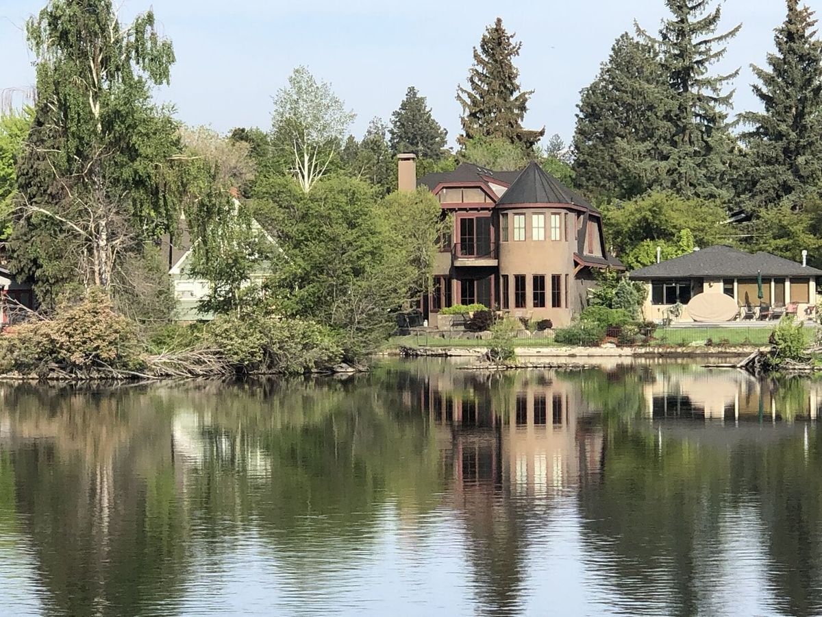 A charming riverside home surrounded by lush greenery and reflected perfectly in calm waters. This serene escape offers peaceful views and a private connection to nature in the heart of Bend.