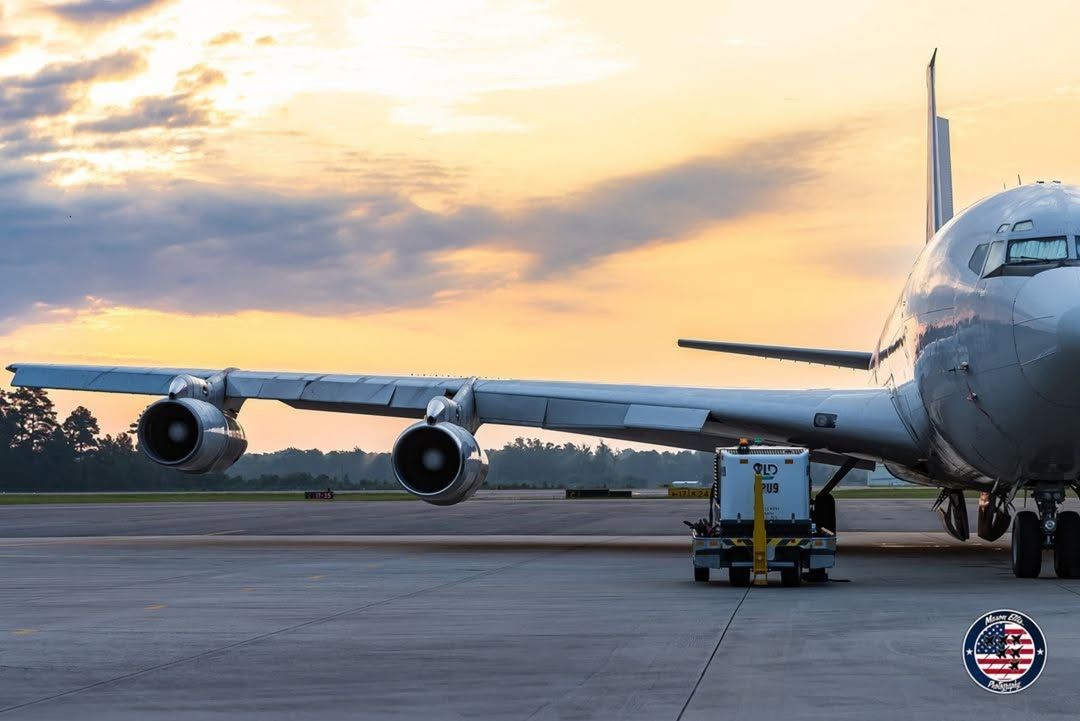 A large passenger airplane sits on the runway at Wilmington International Airport during sunrise with soft orange clouds in the background. This travel photo captures the calm start of a trip to the North Carolina coast and nearby beach destinations.