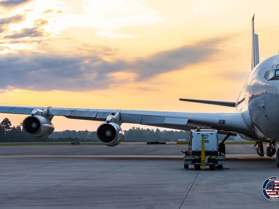 A large passenger airplane sits on the runway at Wilmington International Airport during sunrise with soft orange clouds in the background. This travel photo captures the calm start of a trip to the North Carolina coast and nearby beach destinations.
