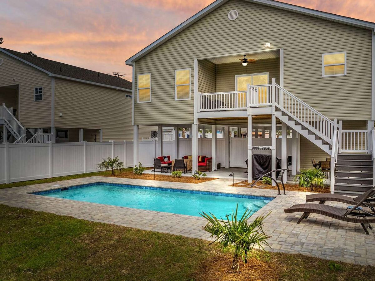 A beautiful two-story home with a sparkling backyard pool, perfect for lounging or evening swims. The open patio and sitting area make it ideal for small groups wanting a quiet beach retreat.