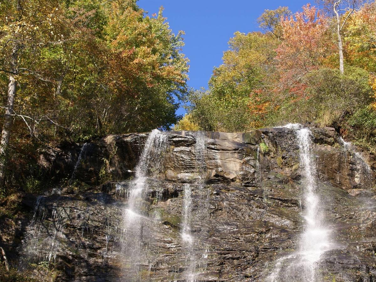 Amicalola Falls cascades down a wide rock face, framed by colorful trees during the fall season. The powerful water flow and open viewing areas make it one of the most photographed waterfalls in Georgia. Visitors often come here for hiking trails, scenic views, and outdoor adventure near the mountains.