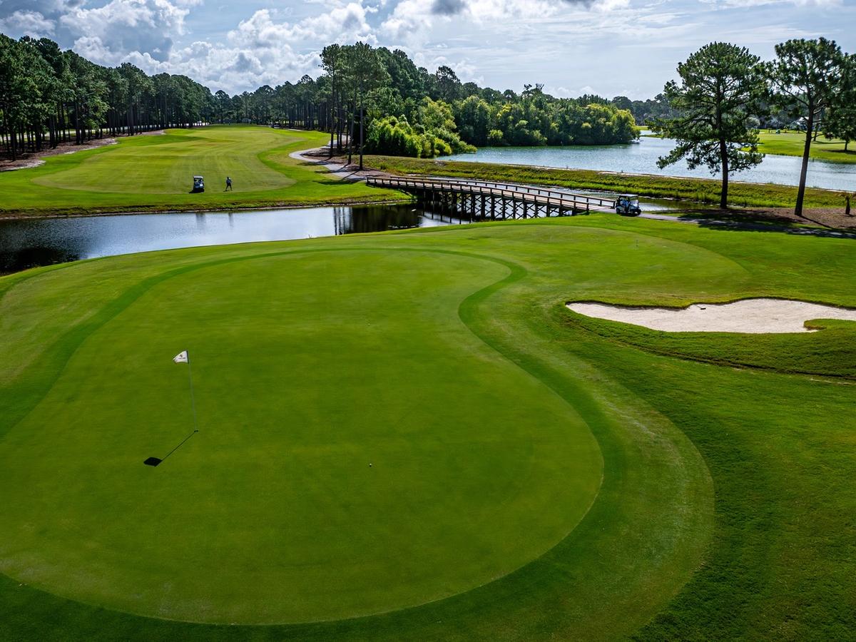 A wide fairway at Sea Trail Golf Resort features smooth greens, a wooden bridge, and water views. This coastal golf course is perfect for a laid-back and scenic round.