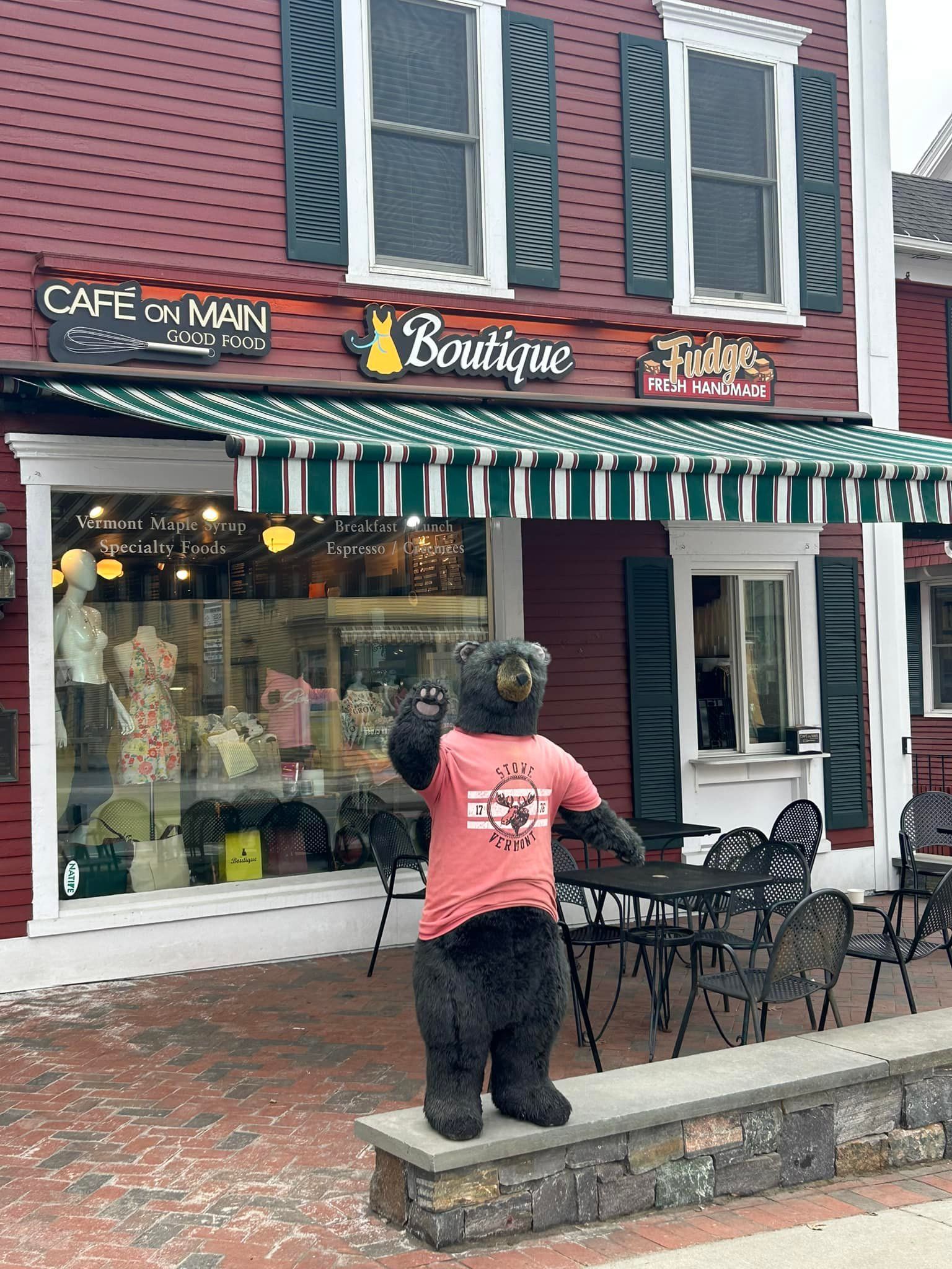 A playful bear mascot stands outside Cafe on Main in downtown Stowe, Vermont, a popular spot for breakfast and coffee. This charming café is a favorite stop for visitors exploring Main Street shops and local boutiques.