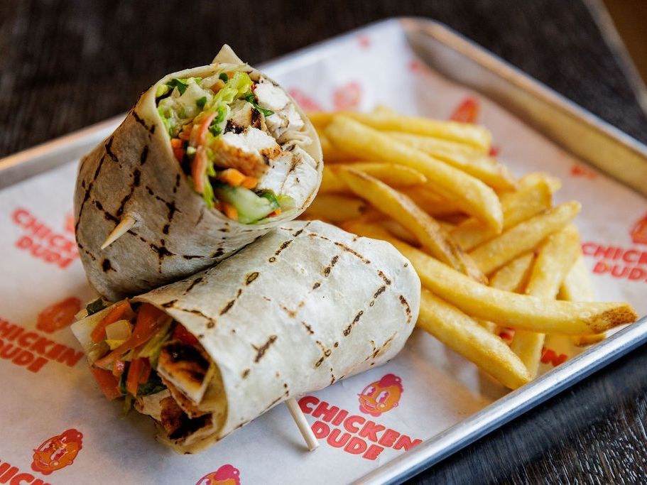 A tasty chicken wrap and crispy fries are served on a tray at Tips Up in Big Sky. Known for its casual vibe, live music, and comfort food, this spot is a go-to for relaxing with friends after a day on the slopes.