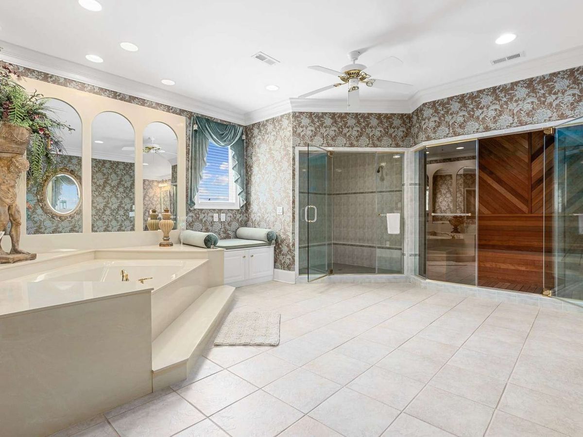 A spacious luxury bathroom at Palmetto Sunset features a large soaking tub, walk-in shower, and private sauna. The bright, spa-like space gives guests plenty of room to relax during a group beach vacation.