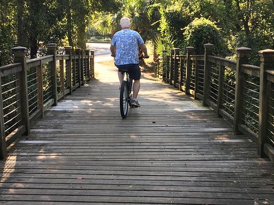 A cyclist enjoys a peaceful ride through Hilton Head Island’s scenic bike trails. The shaded wooden bridges and lush greenery make biking one of the island’s best outdoor activities.