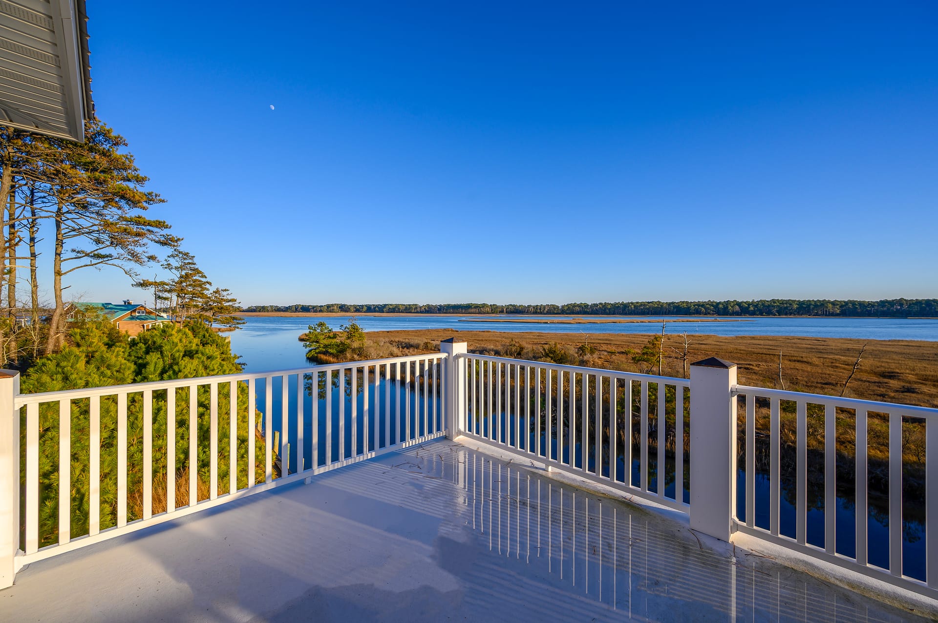 This balcony looks out over a calm marsh and wide blue water, giving you a peaceful place to relax and enjoy the view. The bright sky and still reflections make the whole scene feel quiet and open. It’s the kind of spot where you’d want to sip coffee and watch the day begin.