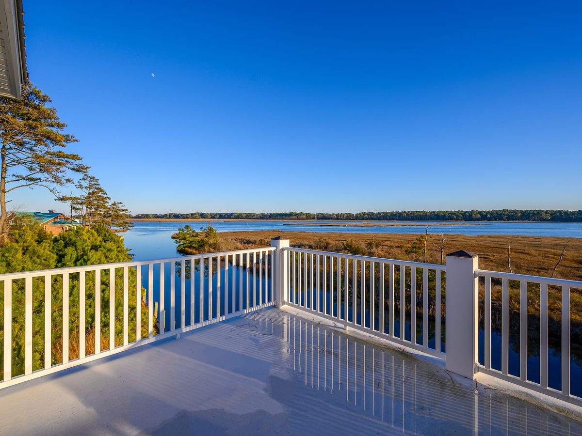 This balcony looks out over a calm marsh and wide blue water, giving you a peaceful place to relax and enjoy the view. The bright sky and still reflections make the whole scene feel quiet and open. It’s the kind of spot where you’d want to sip coffee and watch the day begin.