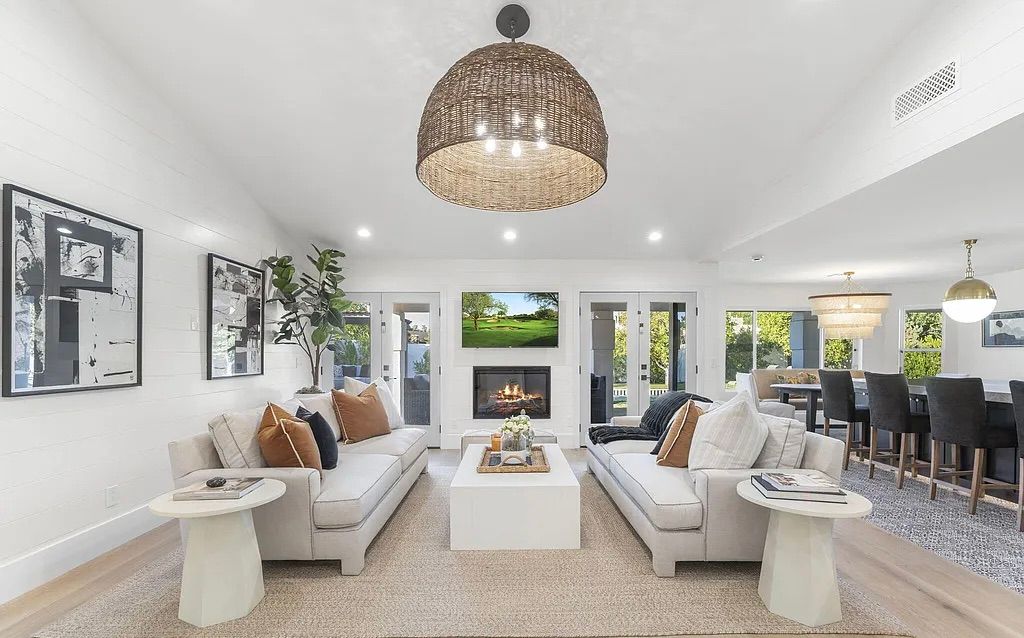 A bright, inviting living space with soft neutral tones, cozy fireplace ambiance, and seamless flow into a stylish kitchen and dining area—perfect for relaxed, elevated living.