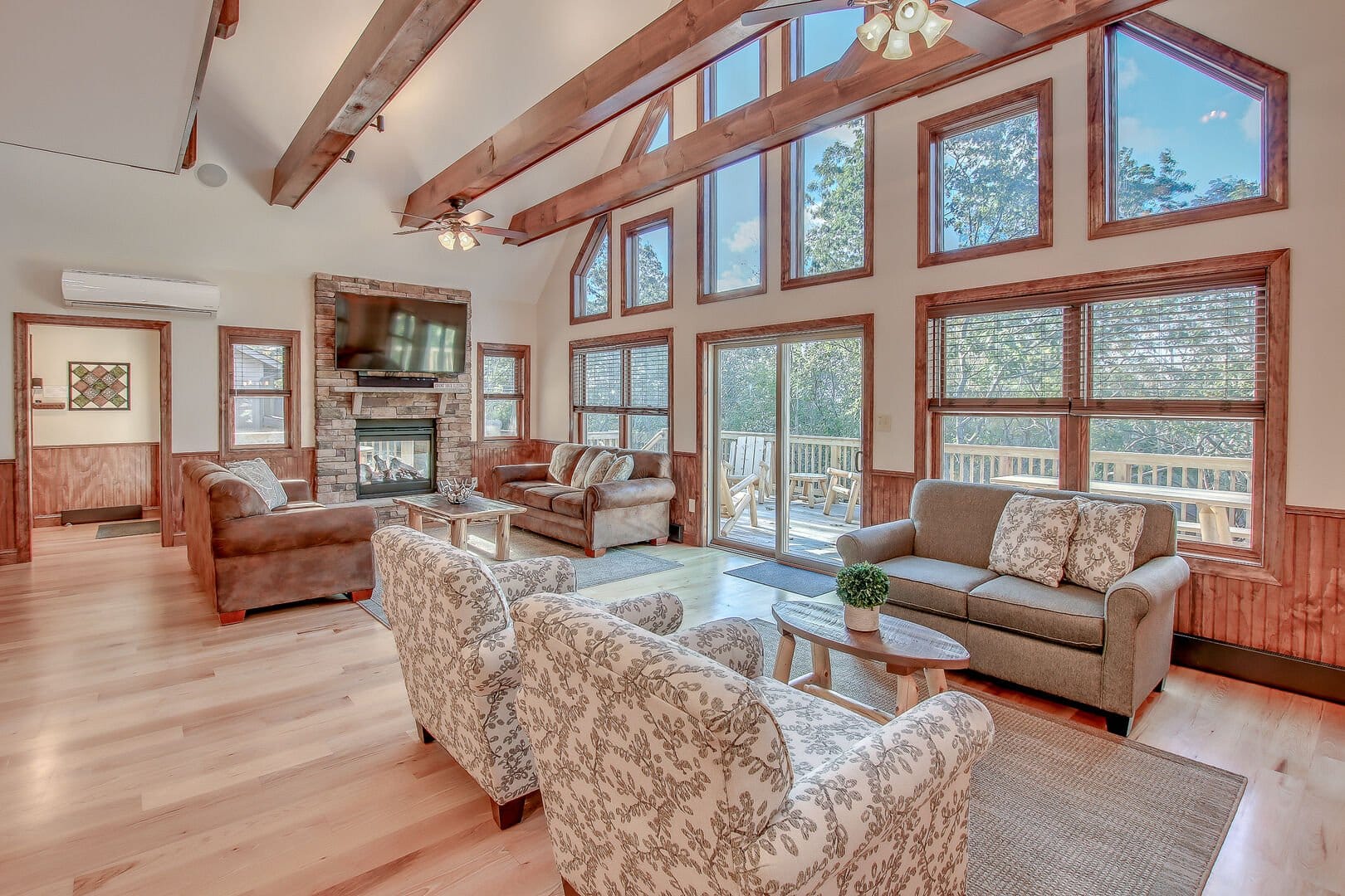 A cozy mountain cabin with a large deck and fire pit sits in a peaceful grassy setting in the Pocono Mountains. Outdoor chairs surround the fire pit, creating the perfect spot for relaxing evenings. This cabin getaway offers a quiet escape surrounded by nature.