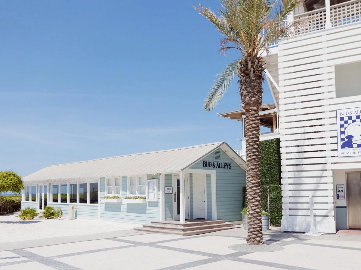 Bud & Alley's restaurant in Seaside, Florida along Scenic Highway 30A with coastal architecture, palm trees, and beach access on a sunny day.