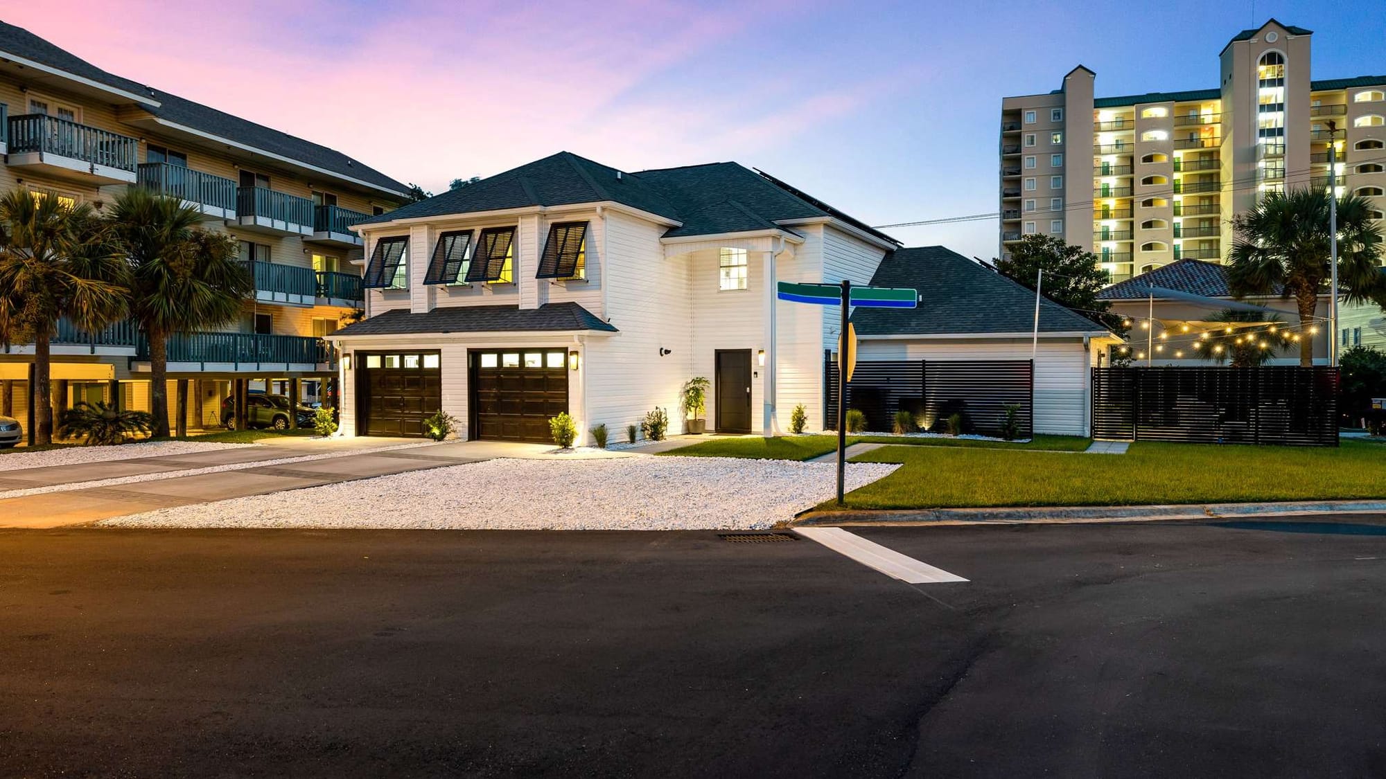 This modern white coastal home glows beautifully at dusk with warm lights and palm trees. Located near the beach and top attractions, it’s ideal for family vacations or group getaways.