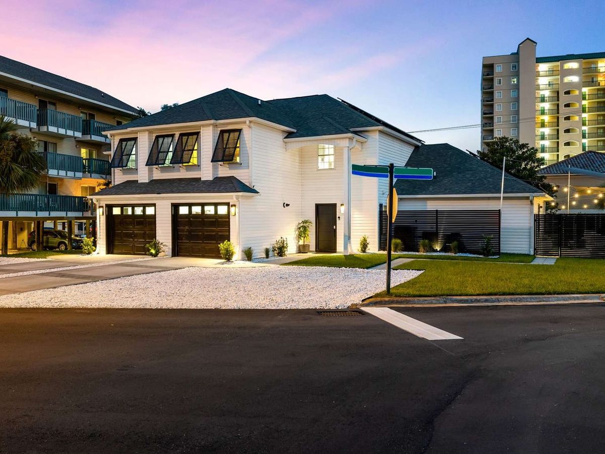 This modern white coastal home glows beautifully at dusk with warm lights and palm trees. Located near the beach and top attractions, it’s ideal for family vacations or group getaways.