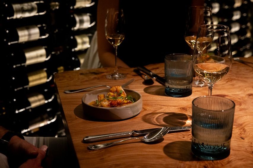 An intimate dinner scene at Sweet Basil in Vail Valley shows wine glasses and a beautifully plated dish under soft lighting. The cozy yet refined setting makes it perfect for a special night out. It’s a top fine dining restaurant in Vail Valley.