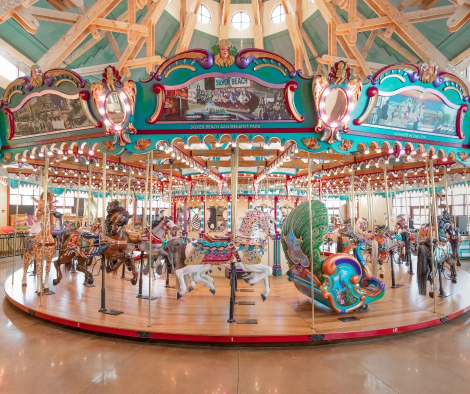 A vibrant and beautifully restored carousel filled with colorful hand-carved horses and whimsical decorations brings joy to visitors of all ages. The bright lights and classic details create a nostalgic, fun atmosphere inside the pavilion.