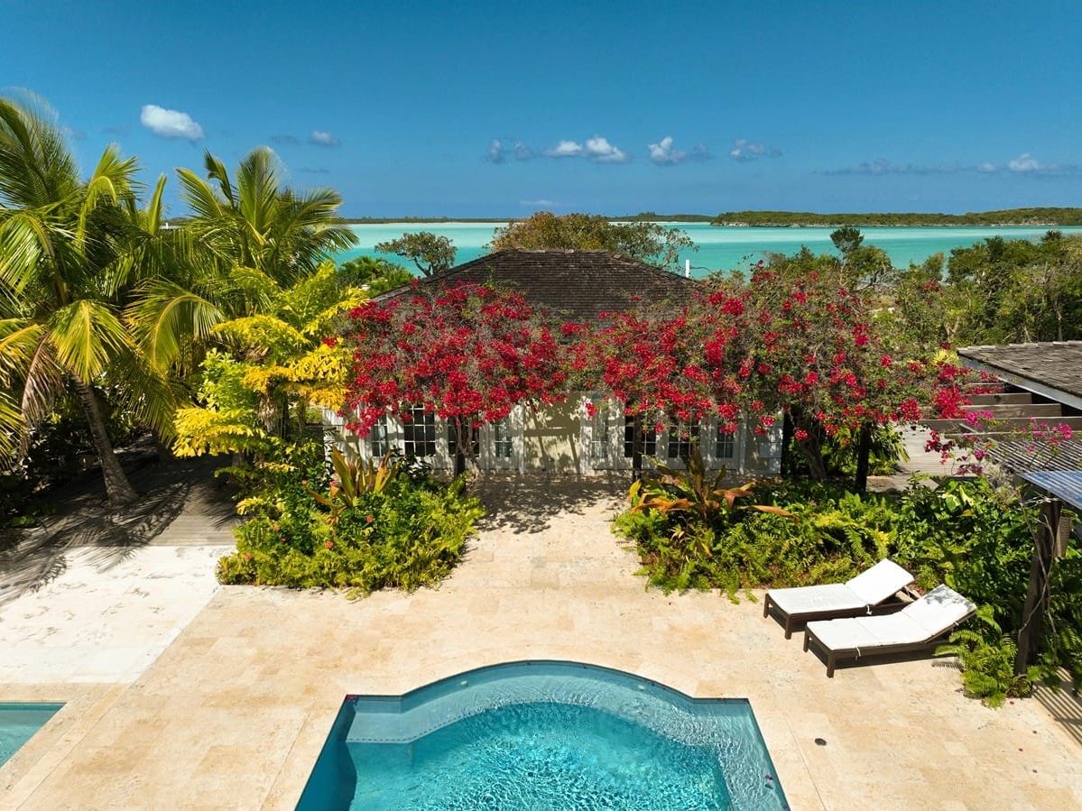 A luxury Bahamian villa surrounded by lush greenery, a sparkling pool, and views of turquoise waters. Staying here offers a peaceful escape with easy access to the islands’ natural beaut