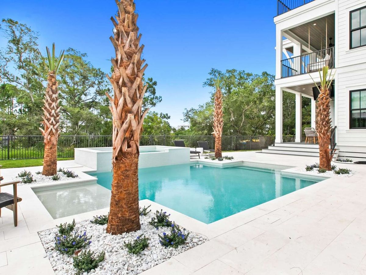 A private backyard pool with clean stone decking, palm trees, and a modern coastal home at South Lake View. This outdoor space is perfect for relaxing after the beach, with plenty of room to lounge, swim, and enjoy the quiet coastal setting.