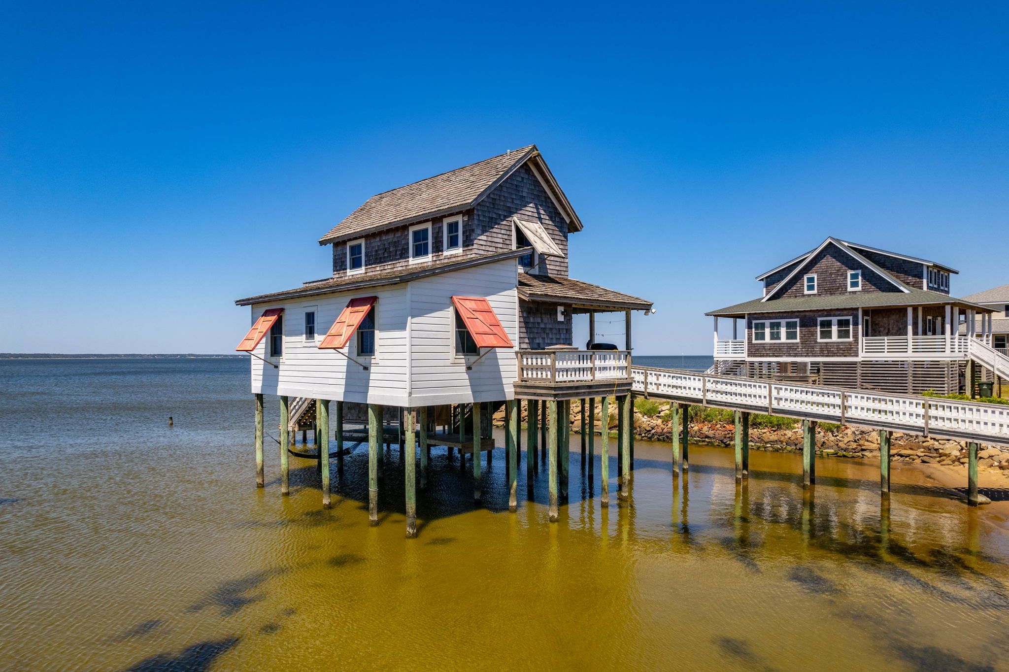 Vacation rental with red window shutters on water with walkway
