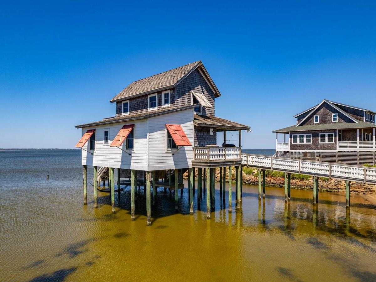 Vacation rental with red window shutters on water with walkway