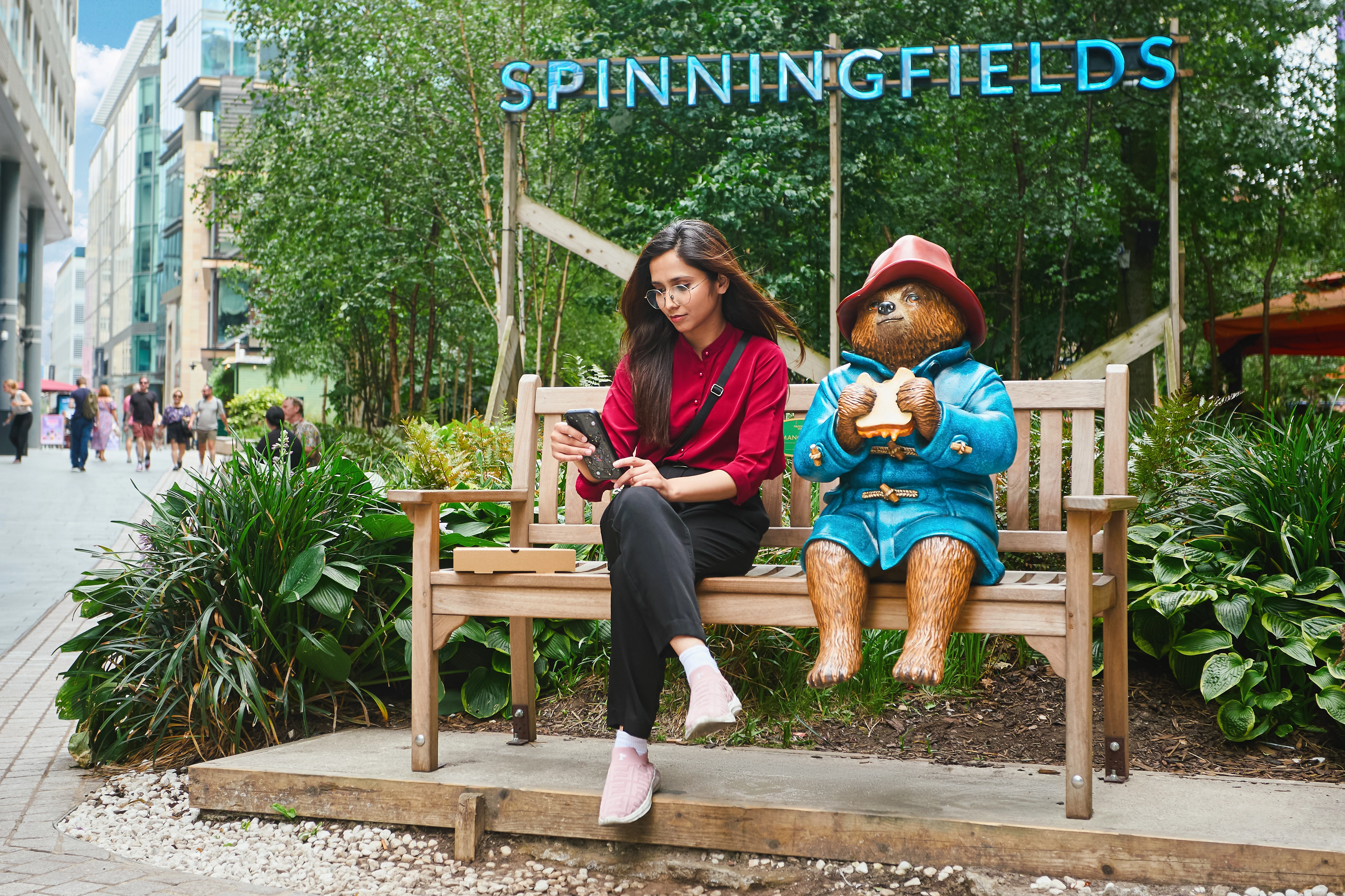 A girl sat with the Paddington Statue