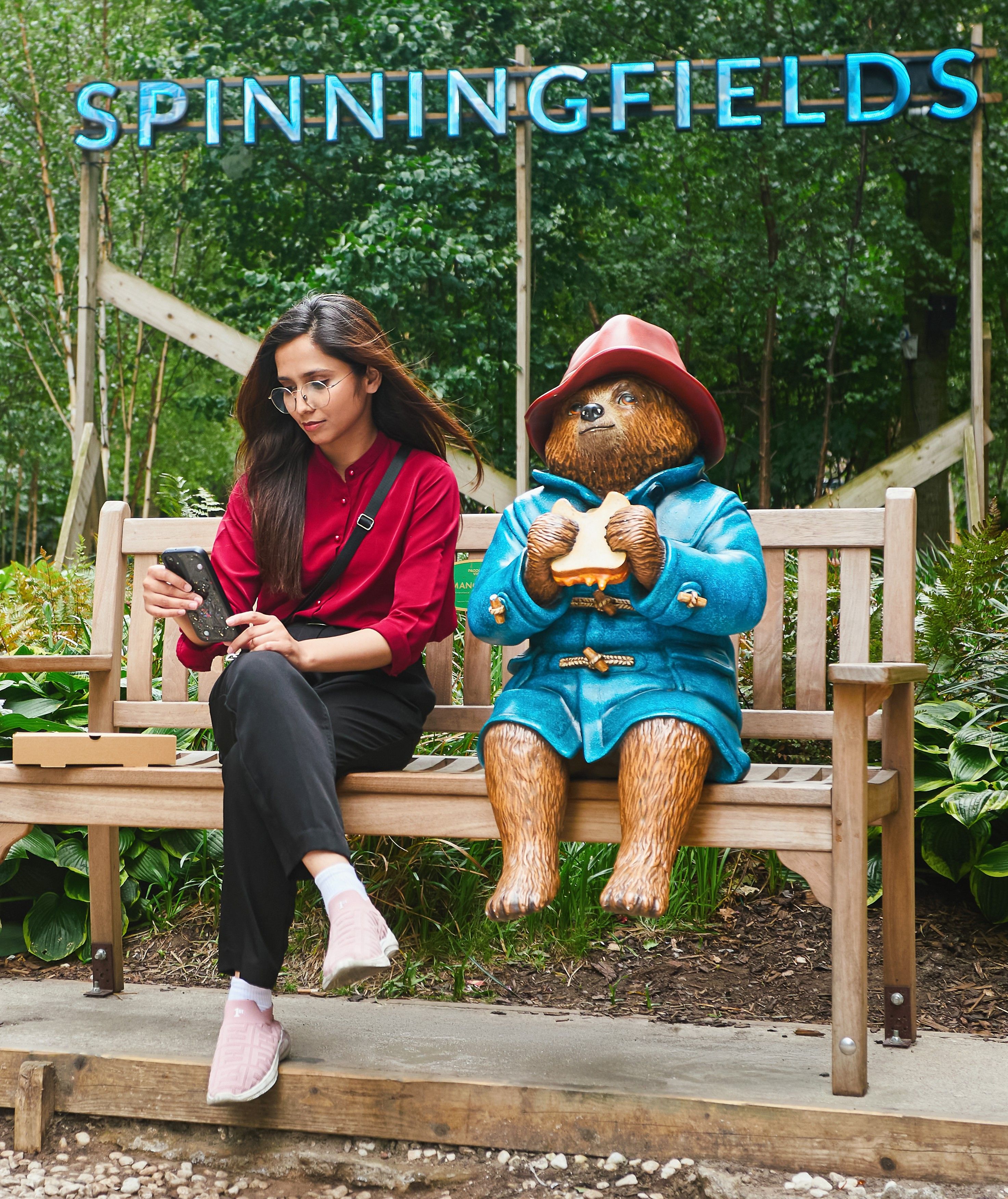 A lady sat with Paddington statue
