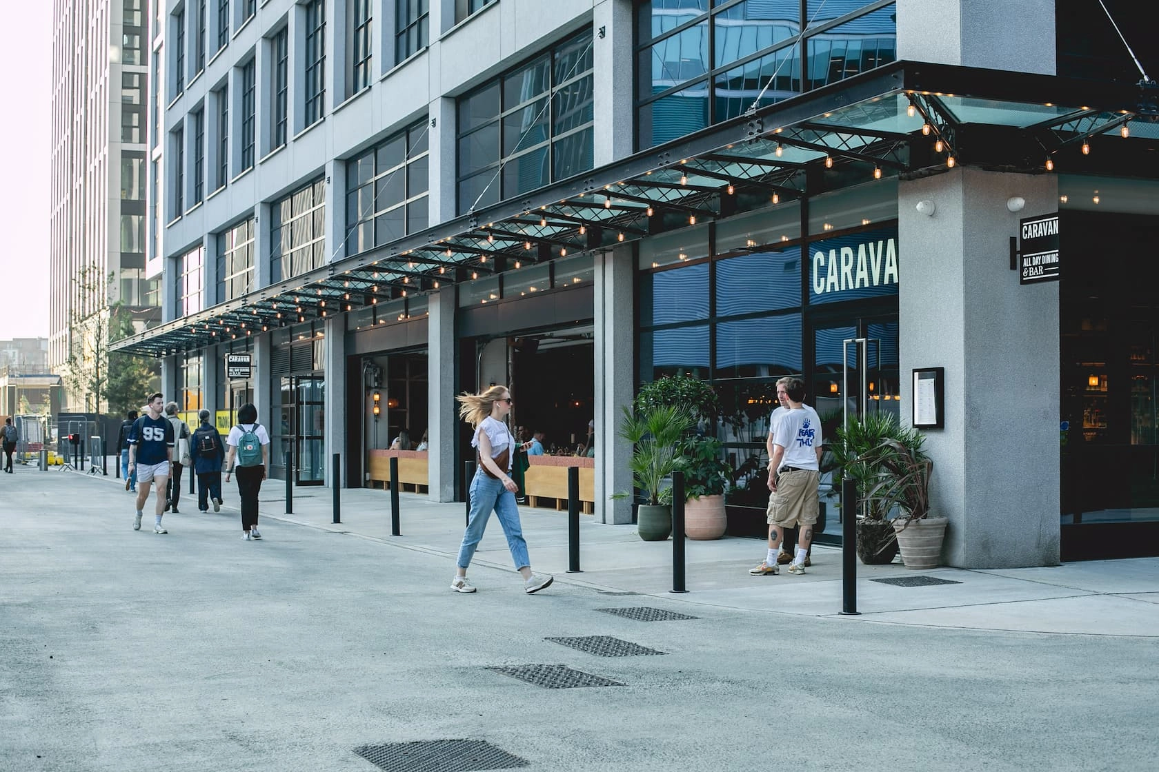 People walking past restaurants and modern buildings