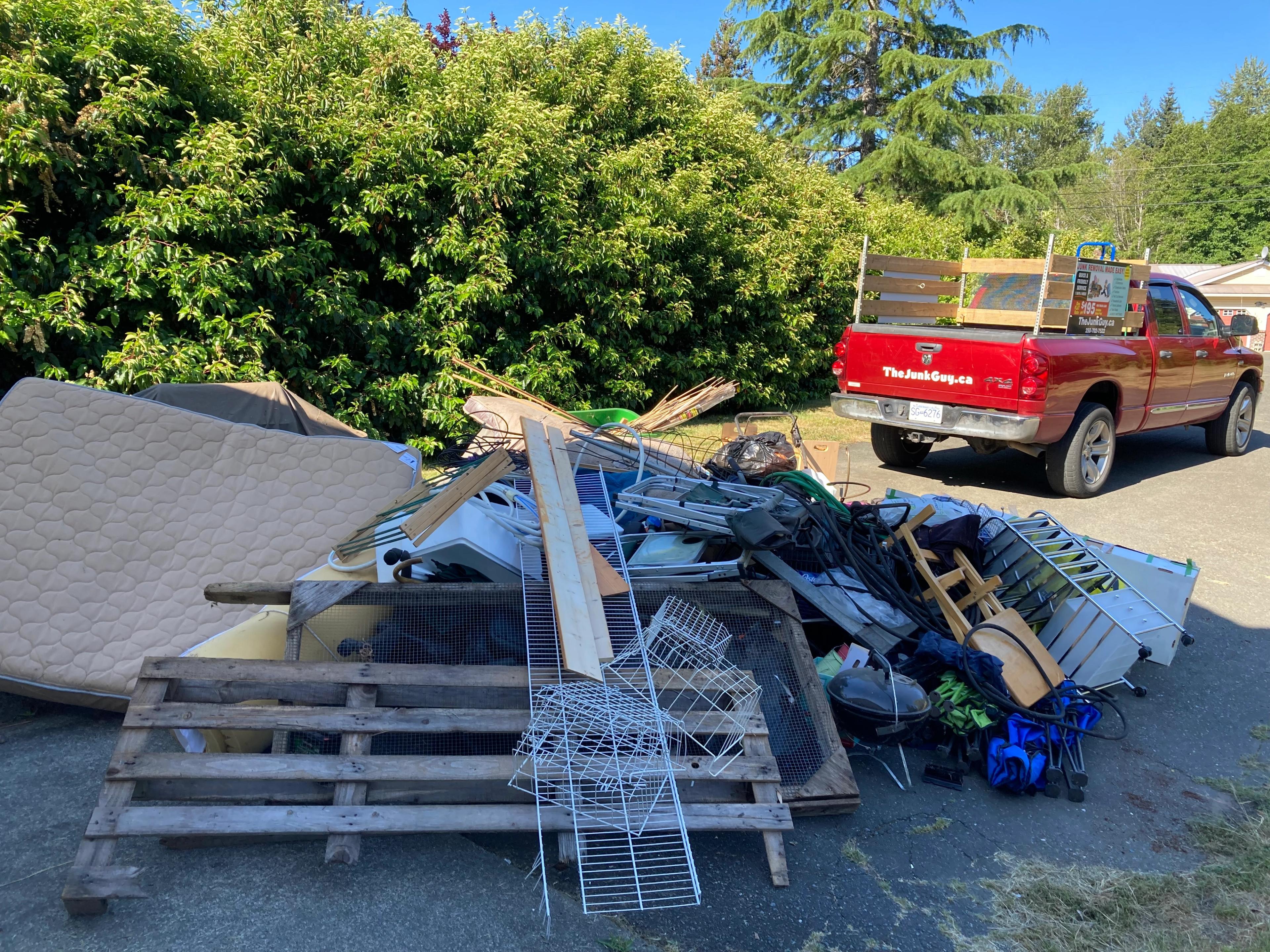 Driveway pile with mattresses, electronics, wood pallet, BBQ, lawnmowers and other assorted junk