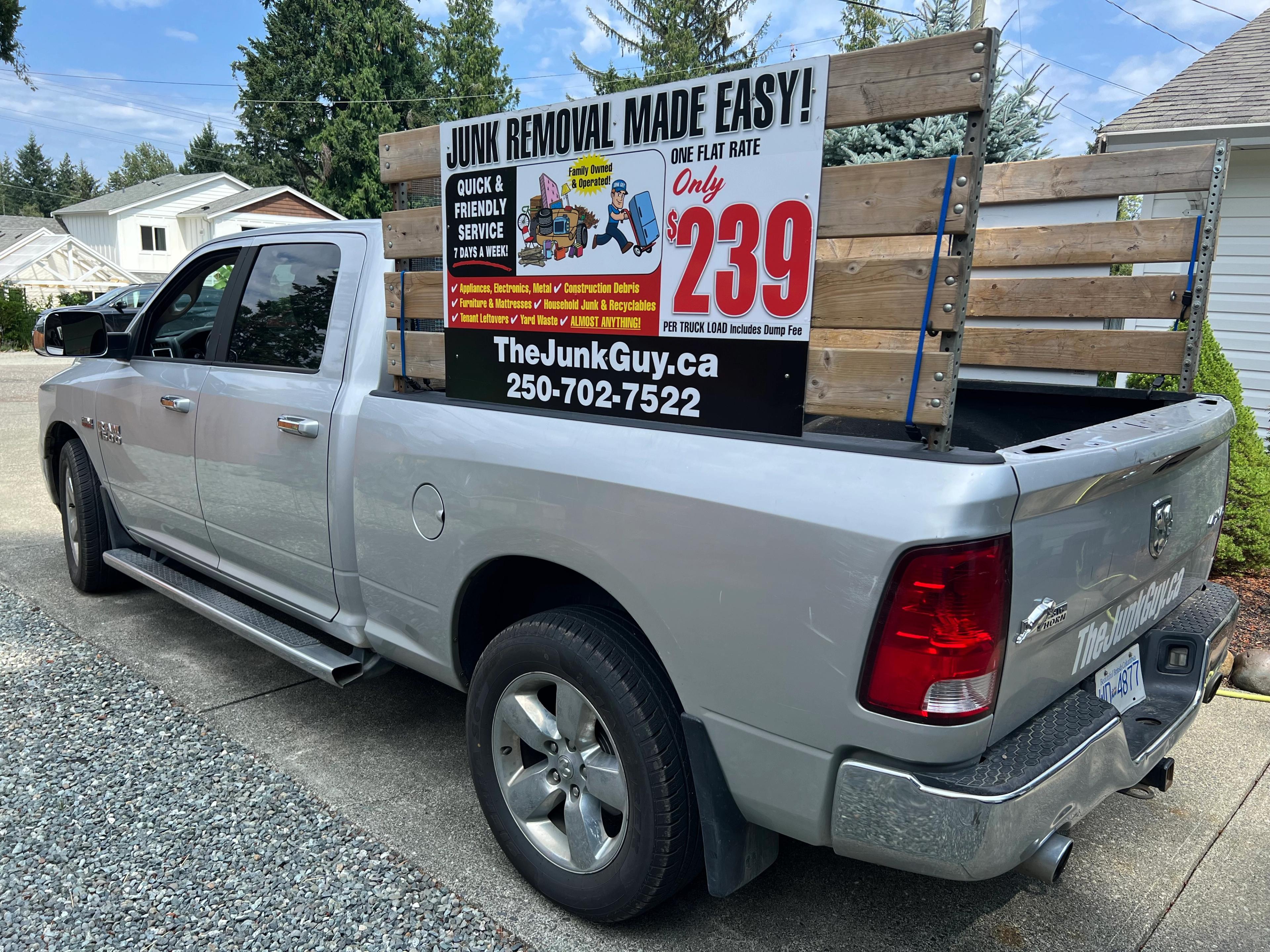 Silver pickup truck with wooden racks and a TheJunkGuy.ca junk removal sign