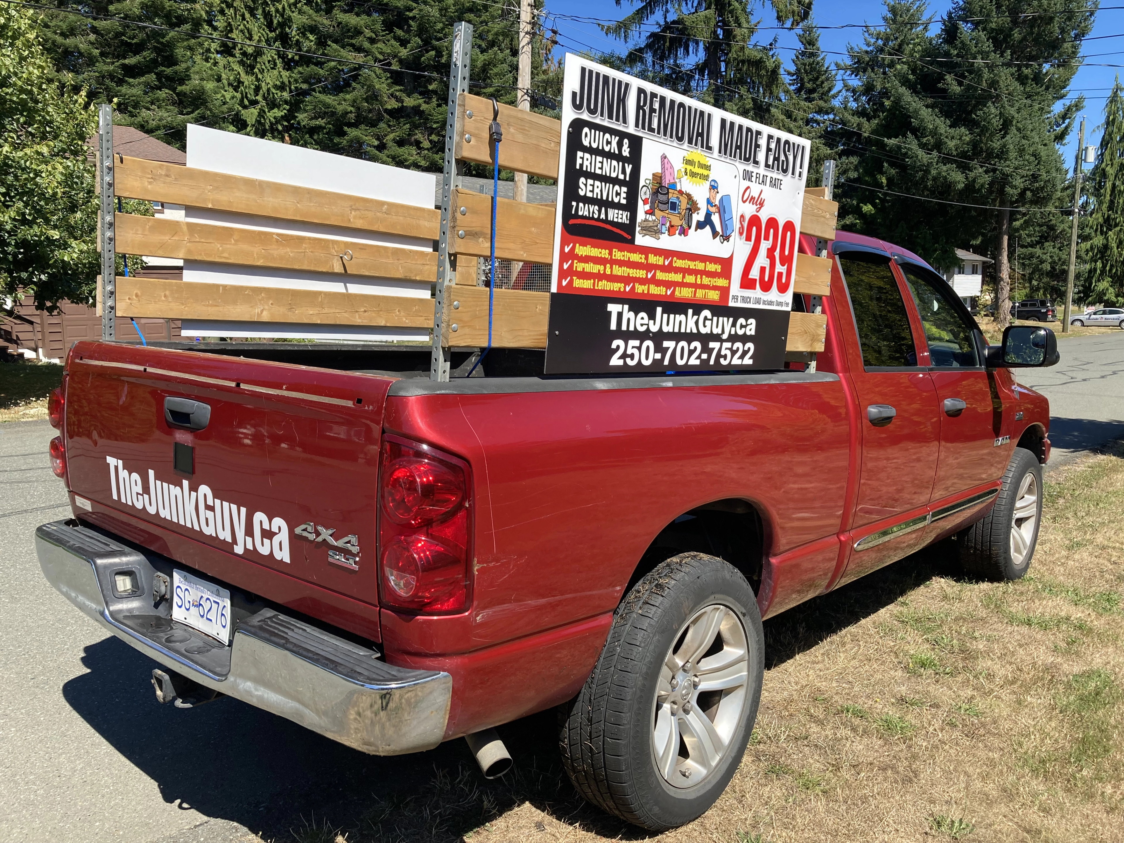 Red pickup truck with wooden racks and a TheJunkGuy.ca junk removal sign