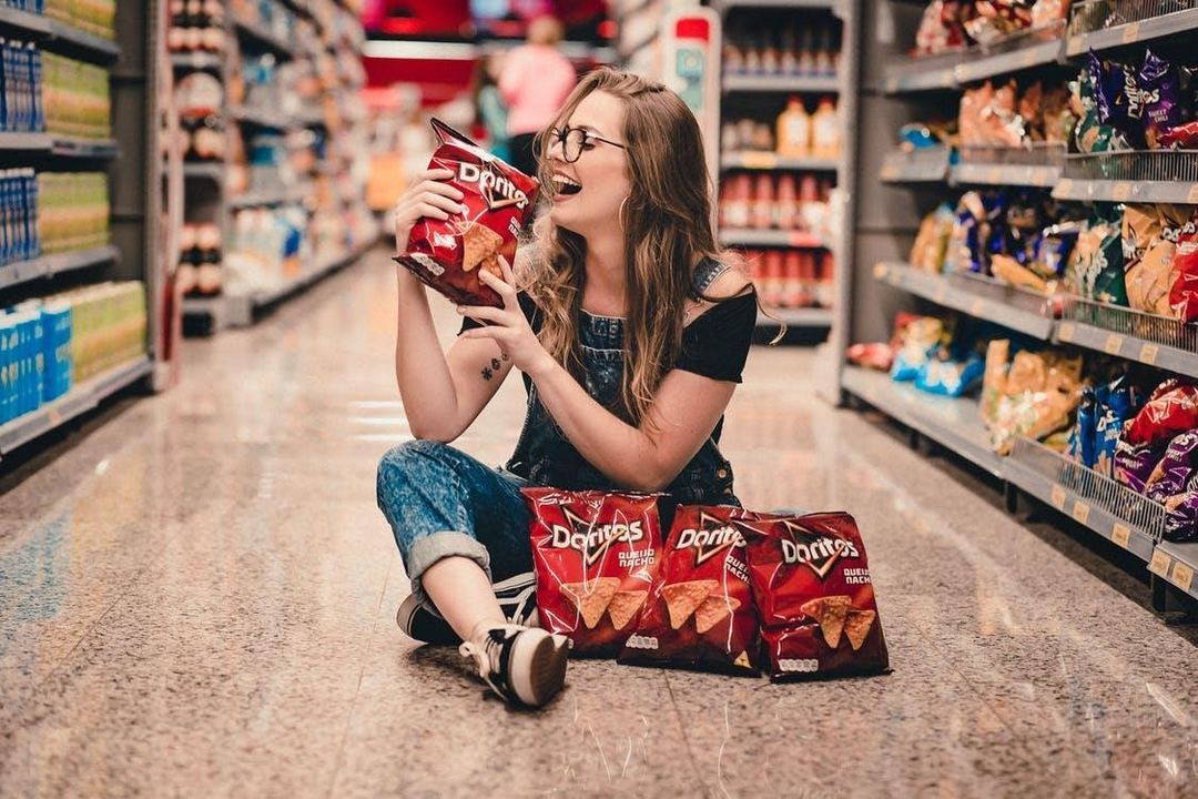 Woman Holding Bag Of Chips having fun in a convenience store