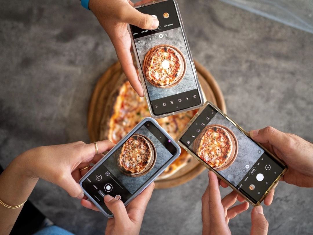 Persons taking a photo of a pizza