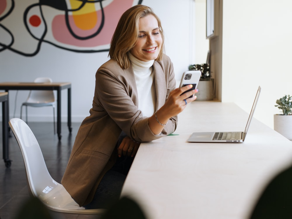 A woman holding a phone in front of a computer