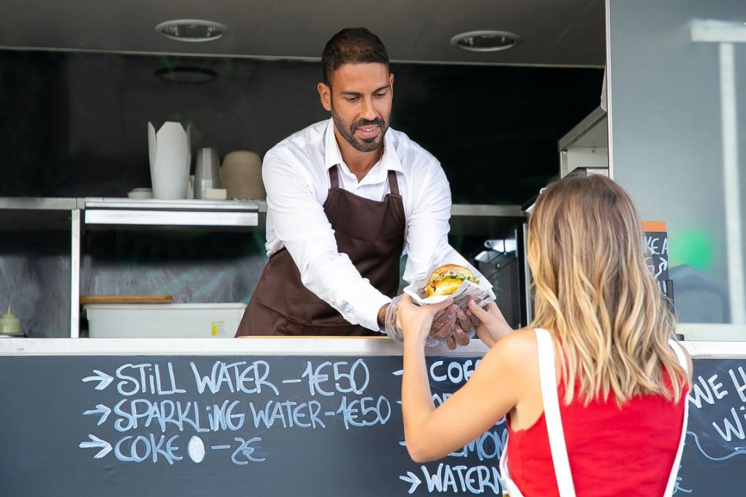 A food truck worker serving a woman
