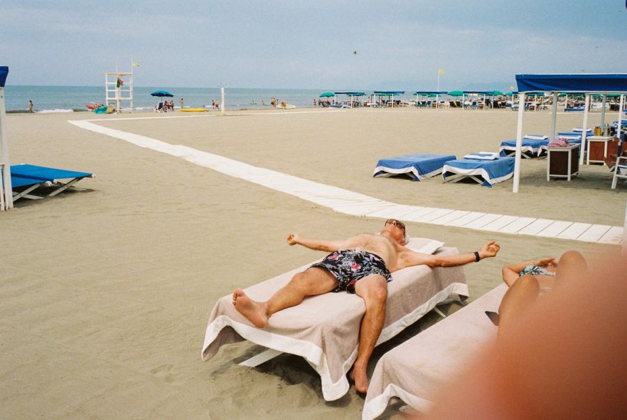 Man sunbathing on a lounger at a near-empty Italian lido. Film photograph by Nicolò Pudel