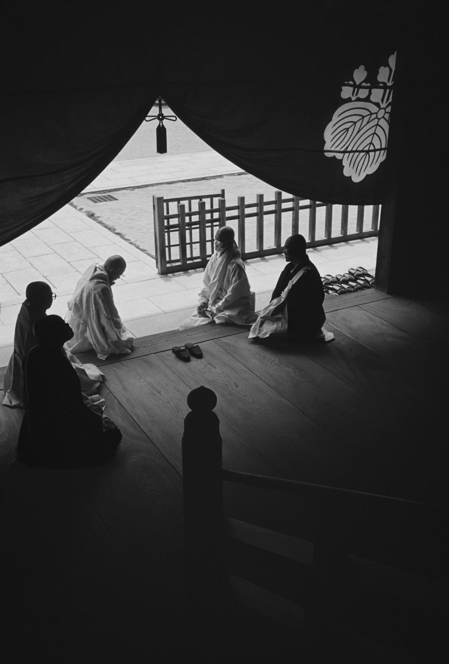 Five people sit on a wooden floor inside a tent with geometric patterns and a cross, film photograph by Nicolò Pudel.