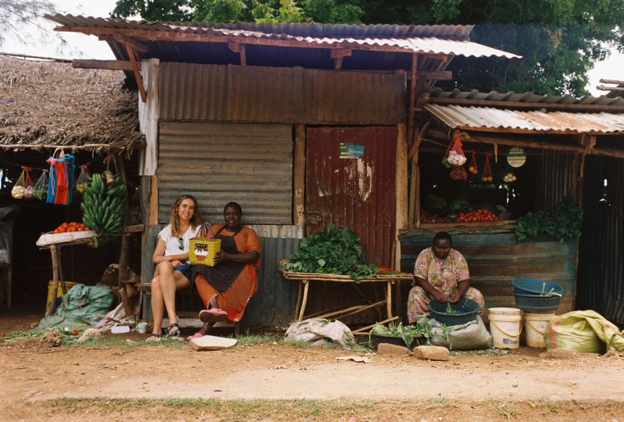 Photographer's partner sitting with vegetable sellers outside a market stall, Msambweni, Kenya. Film photograph by Nicolò Pudel