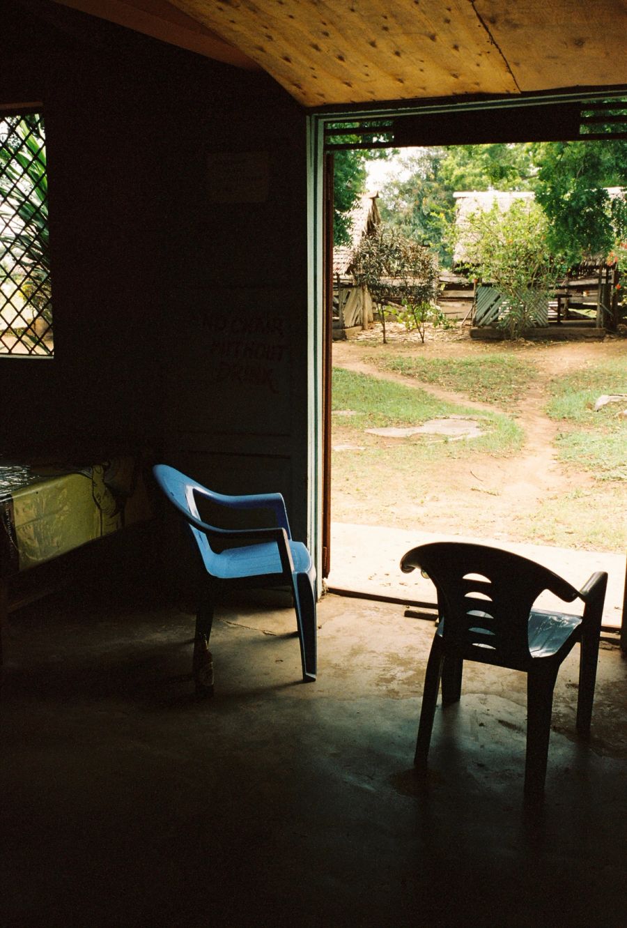Two plastic chairs in a doorway opening onto the village, Msambweni, Kenya. Film photograph by Nicolò Pudel