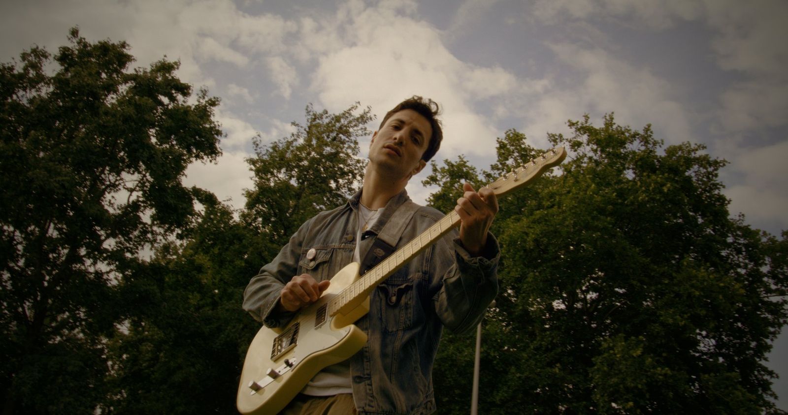 Mid-song, trees at his back.
