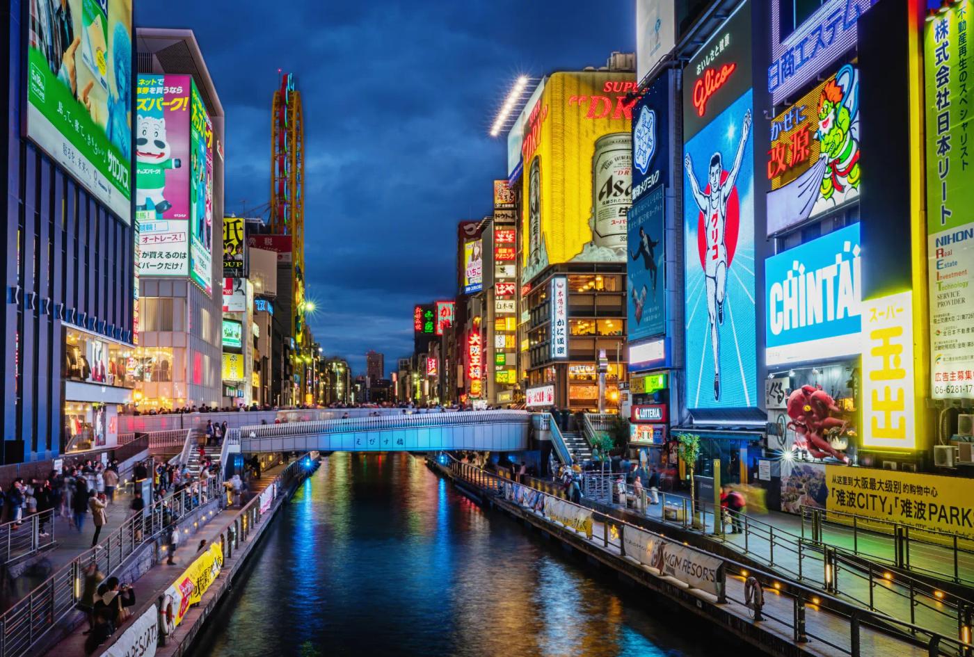 A lit-up downtown district in Osaka with a river running through the middle