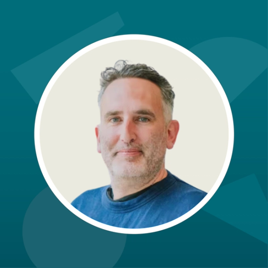 A headshot of Adam Wignall against a teal background