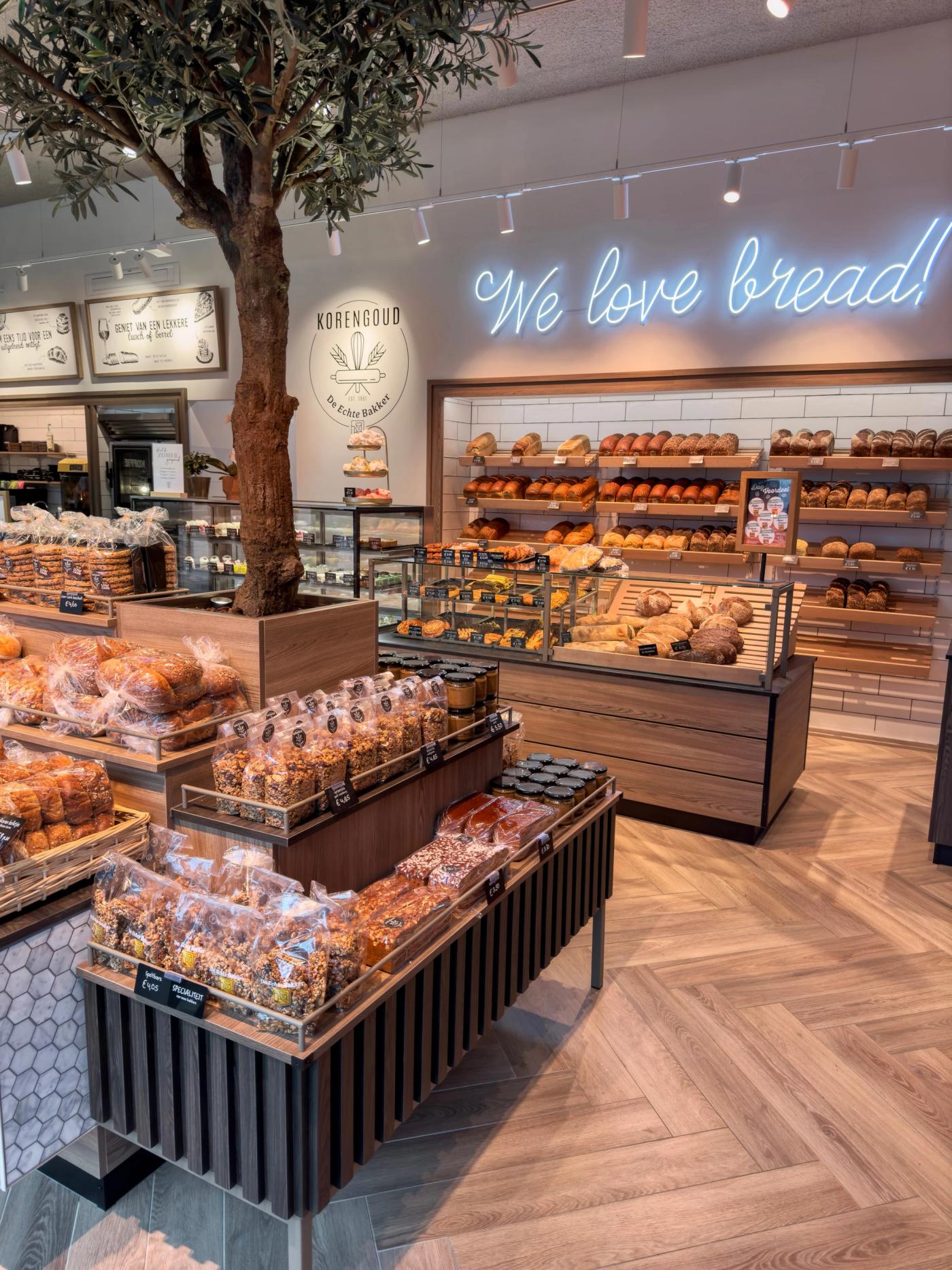 Broodtafel rond de olijfboom bij Korengoud in Rosmalen, met de neonletter op de achterwand.