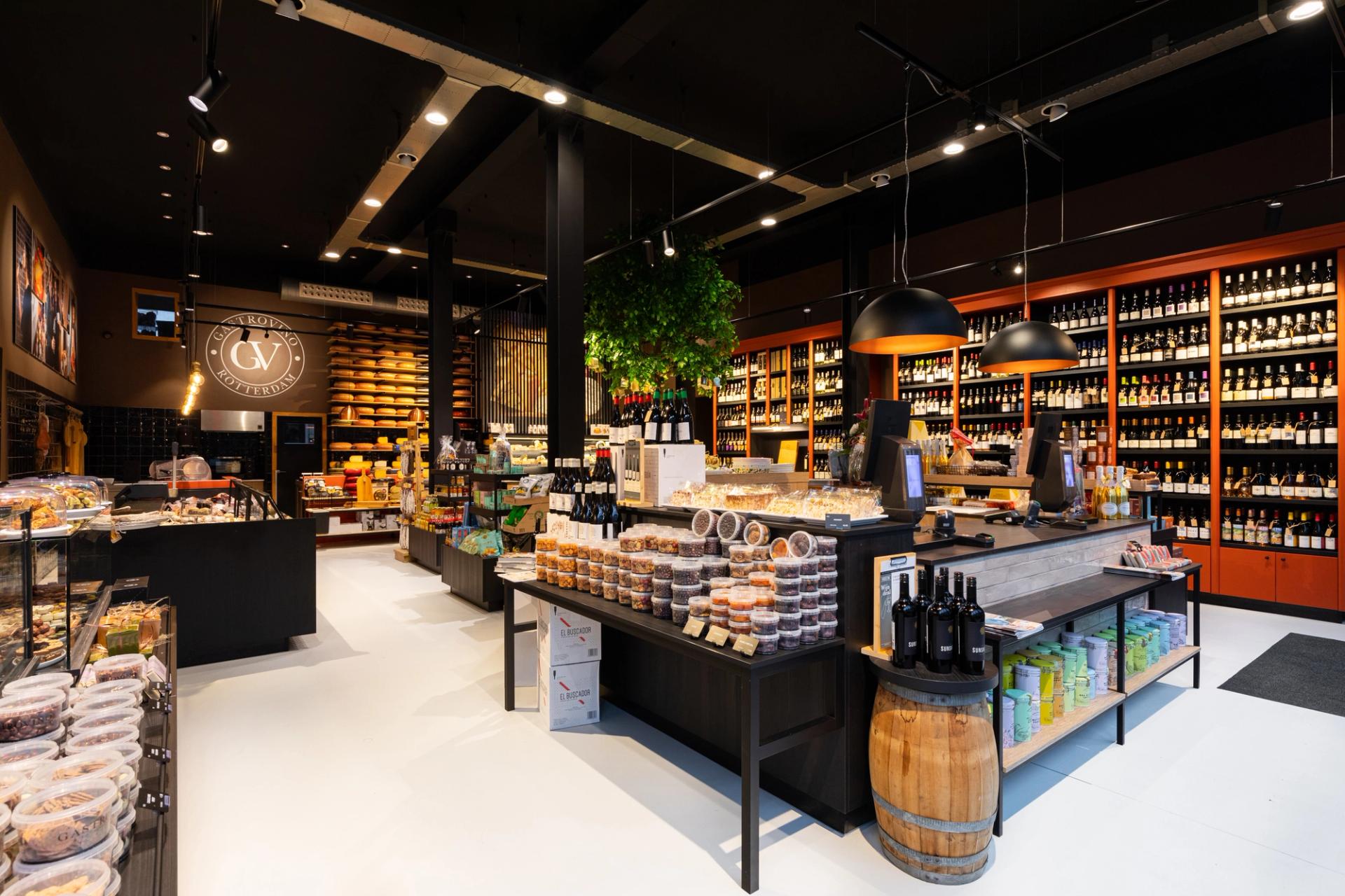 Modern winkelinterieur van Gastrovino Rotterdam, ontworpen en gebouwd door Infrashop, met maatwerk wijnpresentatie, kaas, delicatessen en een warme bourgondische uitstraling.