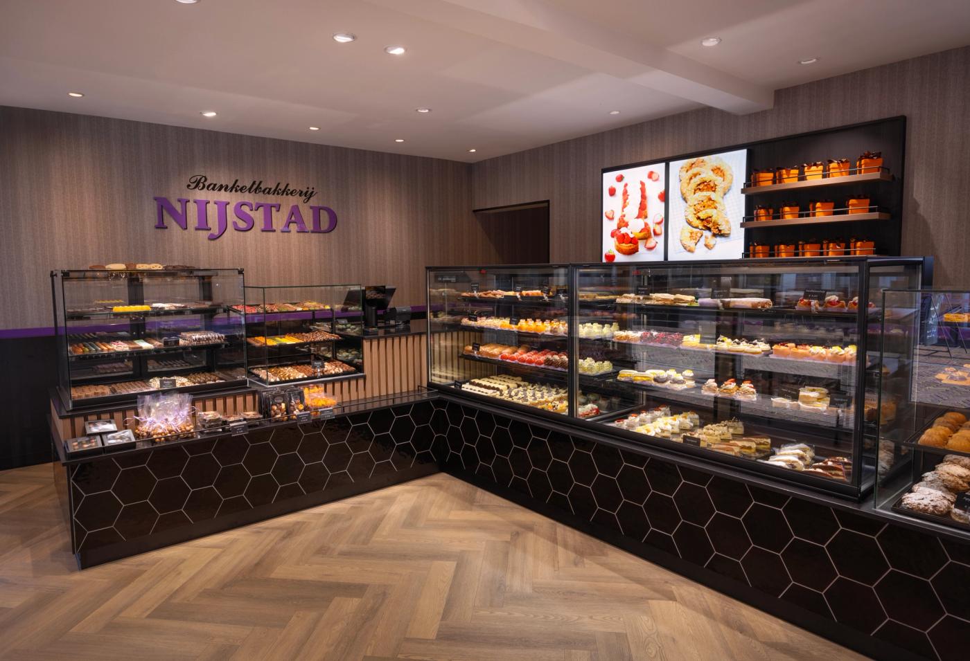 “Stijlvol winkelinterieur van Banketbakkerij Nijstad met luxe gebaksvitrines, warme houttinten, ambachtelijke koekpresentatie en karakteristieke paarse accenten, ontworpen en gebouwd door Infrashop.”