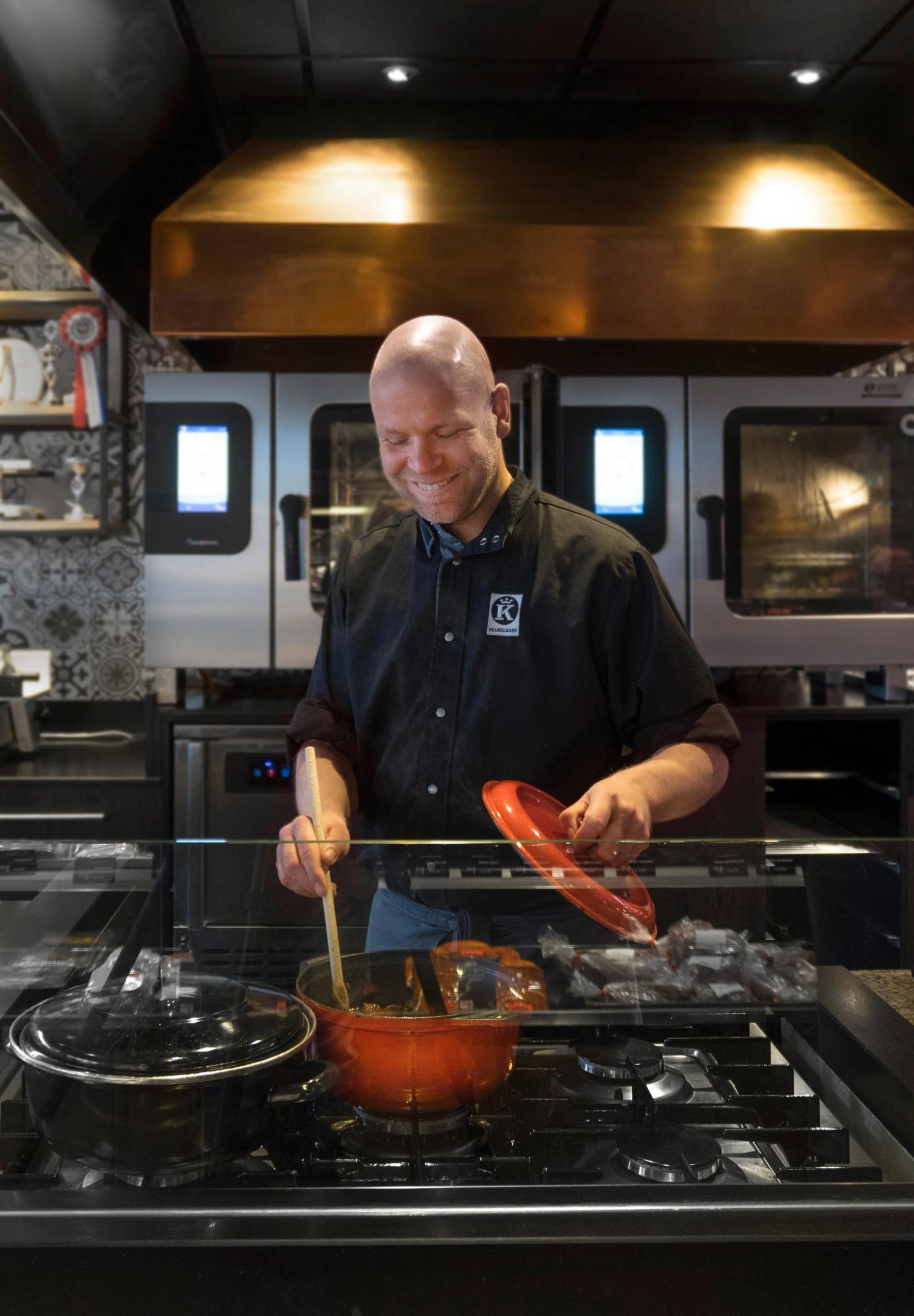 Slager aan het fornuis in de open keuken onder de koperen schouw bij 't Hof van Blankendaal.