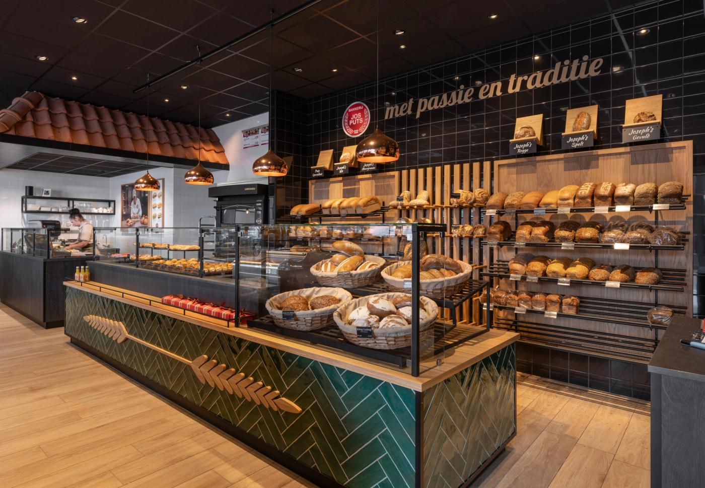 Modern winkelinterieur van Bakkerij Jos Puts in Echt, met royale ambachtelijke broodpresentatie, groene tegelaccenten, warm hout en maatwerk winkelmeubilair ontworpen door Infrashop.