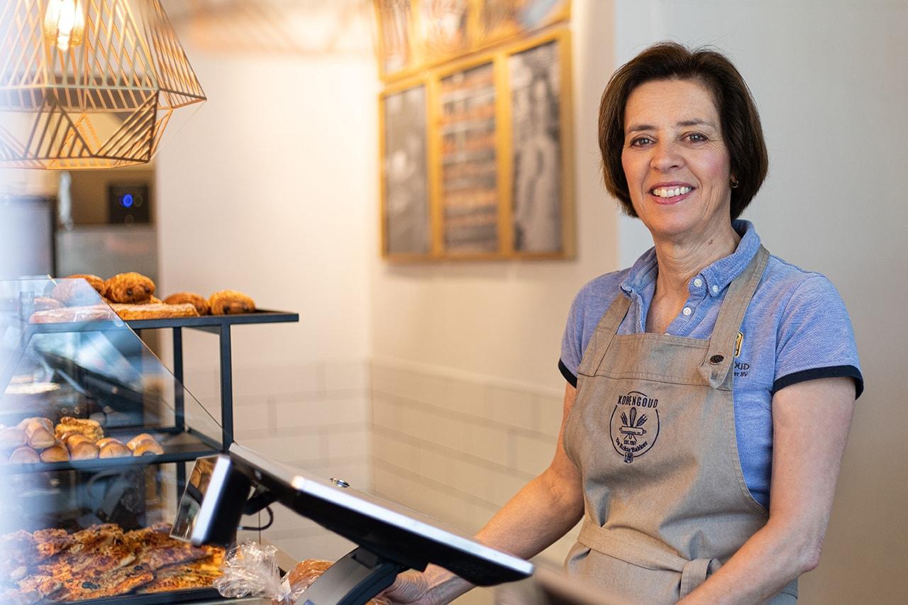 Medewerker van Korengoud achter de kassa in de winkel in Den Bosch.