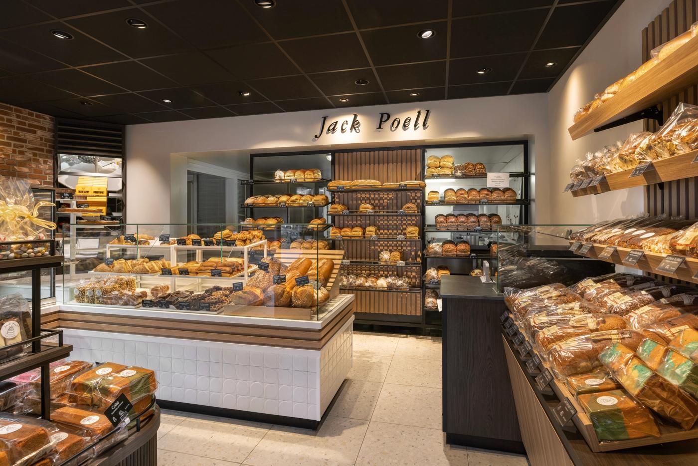 Modern winkelinterieur van Bakkerij Jack Poell in Eindhoven, met luxe brood- en banketpresentaties, warme houtaccenten, lichte tegels en maatwerk winkelmeubilair van Infrashop.